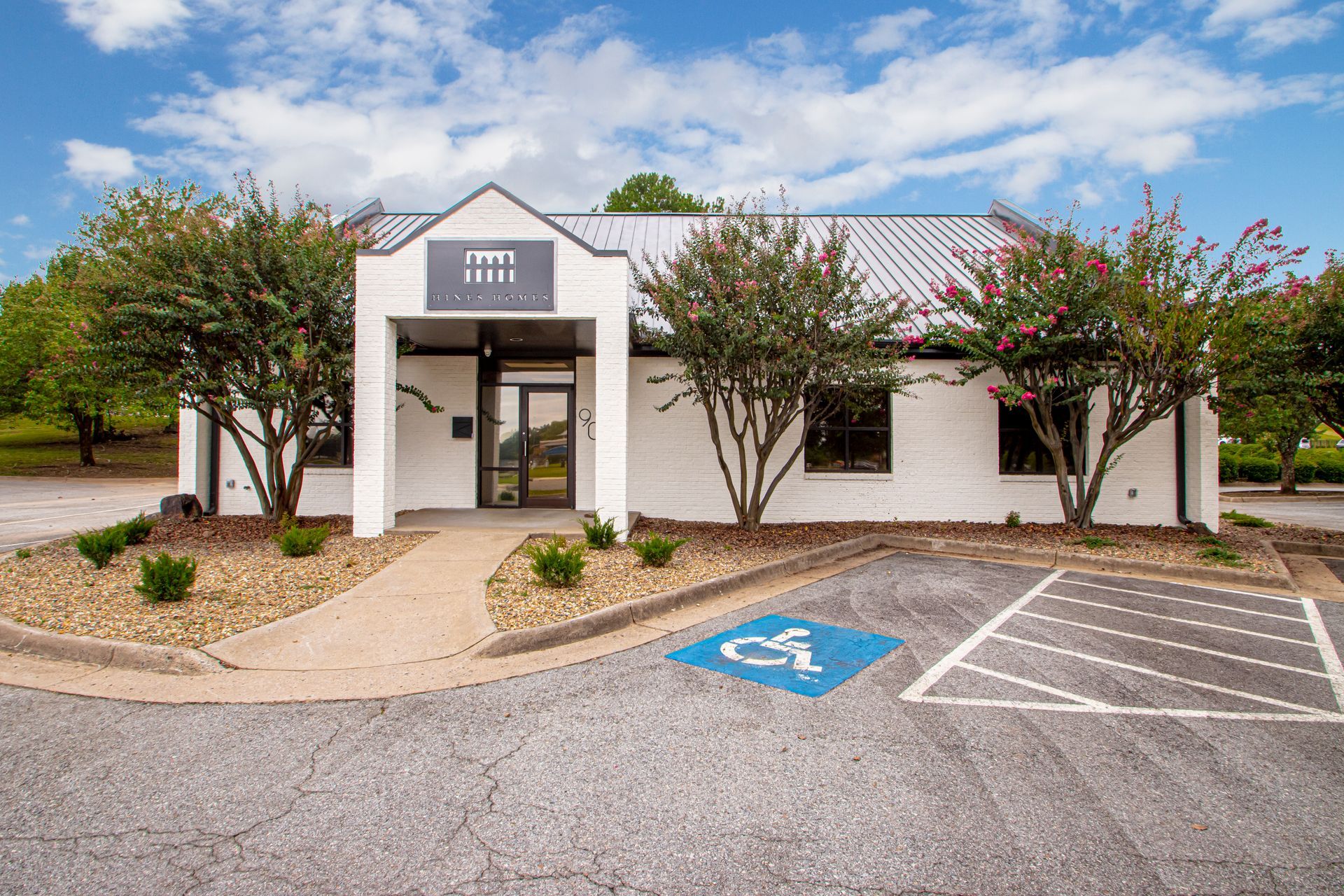 Exterior of a small white building with a covered entrance and handicap parking spaces in front
