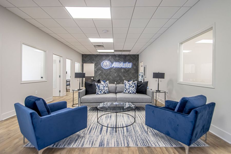 Modern office lounge with blue chairs, gray sofa, glass tables, and a backlit company logo wall