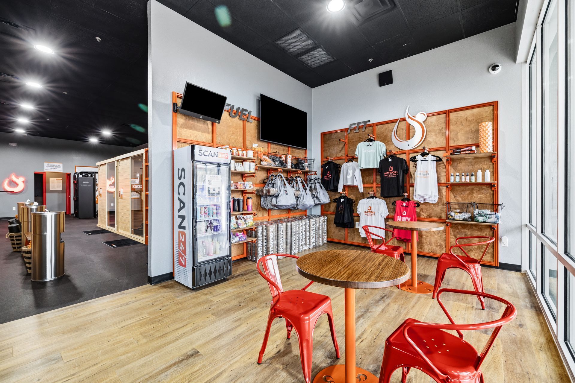 Retail showroom with shelves, display shelves, and red chairs around a round table on a wood floor