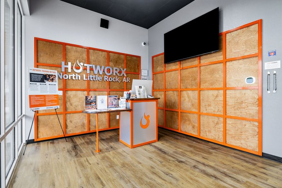 Modern lobby with orange-framed wall panels, a reception desk, and a large black display screen