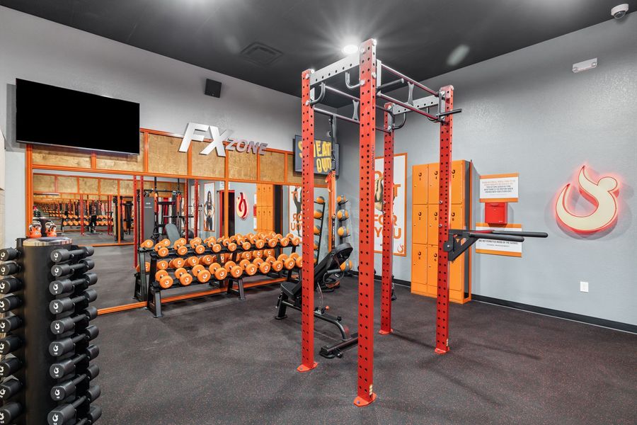 Modern gym with red squat rack, dumbbells, mirrors, and black rubber flooring