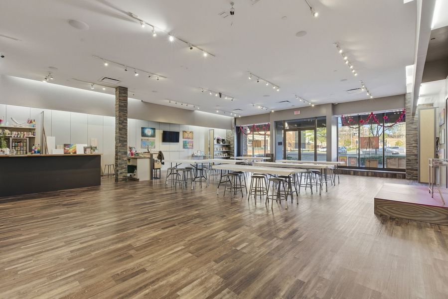 Spacious modern event hall with wood floors, tables, chairs, and large windows.
